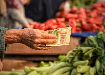 Cropped image of hand holding currency at market stall