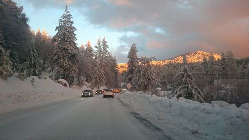 Cars on road against snowcapped mountains during winter