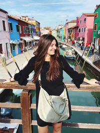 Young woman looking away while standing against buildings