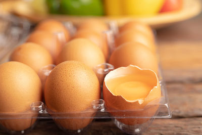 Close up eggs of chicken and yolk with broken in plastic box on the wooden table.