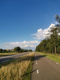 Road amidst field against sky