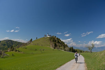 Full length of people on grassy field against sky