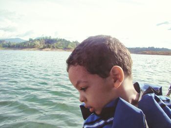 Close-up of boy in river against sky