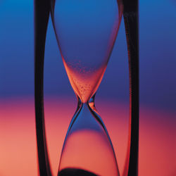 Close-up of hourglass against colored background