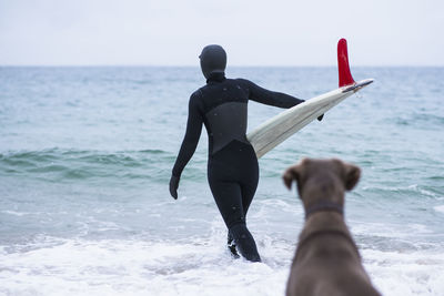 Young woman and her dog going winter surfing in snow