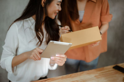 Woman holding digital tablet discussing with coworker in home office