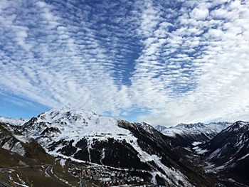 Scenic view of snow covered mountains against cloudy sky