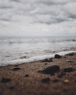 Close-up of pebbles on beach against sky