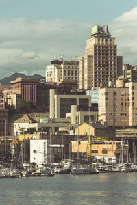 Sea by buildings in city against sky