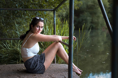 Portrait of woman sitting on pier by lake