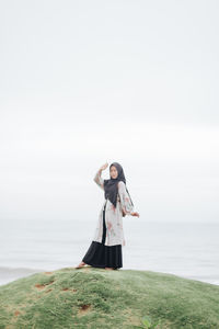 Woman standing by sea against clear sky