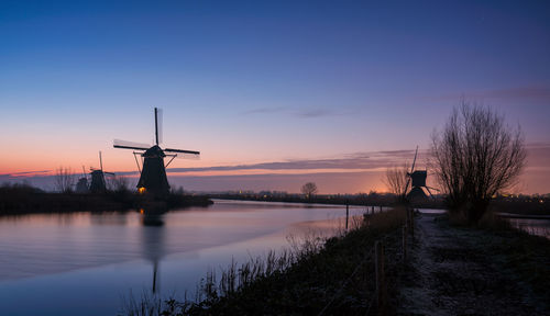 Silhouette of traditional windmill against sky during sunset