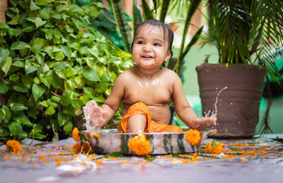 Cute toddler baby boy bathing in decorated bathtub at outdoor from unique perspective