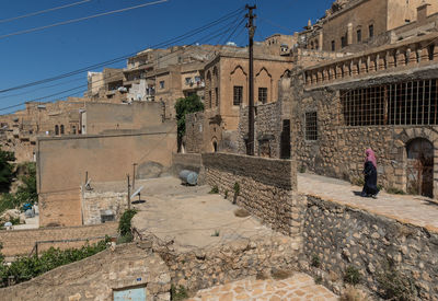 People walking on old building in city against sky