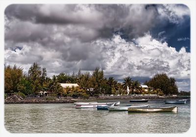 Boats in sea against cloudy sky