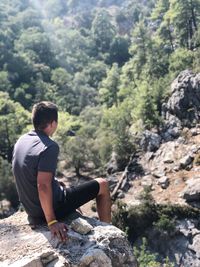 Man sitting on rock in forest