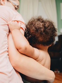 Midsection of mother embracing with son at home