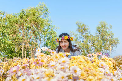 Portrait of smiling young woman against yellow flowering plants