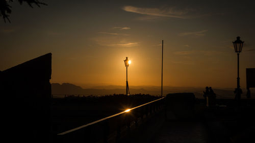 Illuminated street against sky during sunset