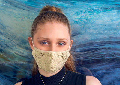 Portrait of girl wearing flu mask against blue background