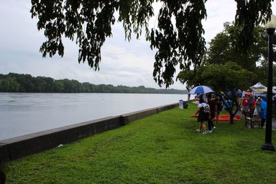 People by lake against sky