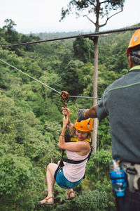 Full length of woman zip lining at forest