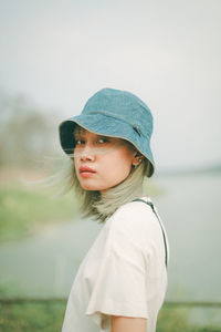 Portrait of teenage girl standing against water