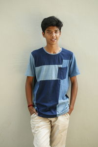 Portrait of boy standing against wall