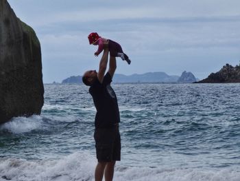 Side view of man playing with daughter at beach 