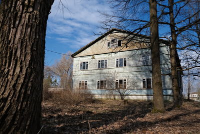 Abandoned building by trees against sky