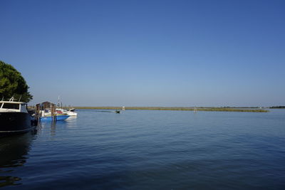 Boats sailing in sea against clear sky