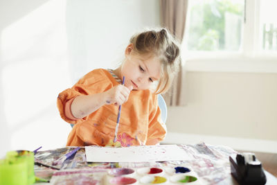 Young girl sitting and painting inside