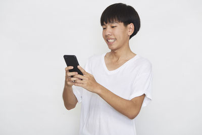 Young man using mobile phone against white background