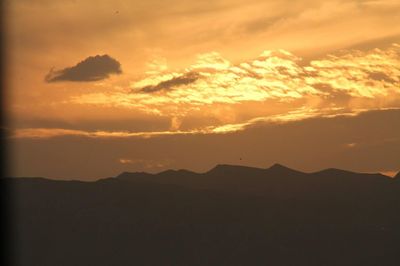 Silhouette mountains against dramatic sky during sunset