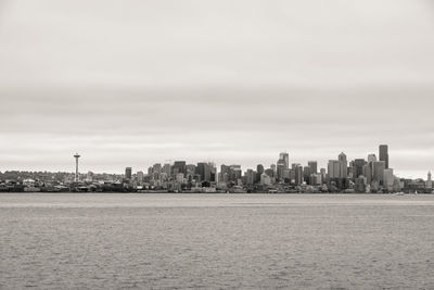 Sea by buildings against sky in city