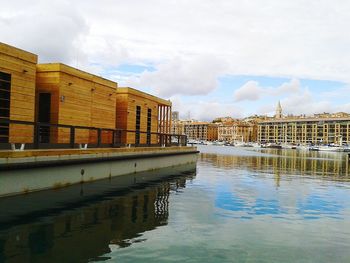 Bridge over river by buildings against sky