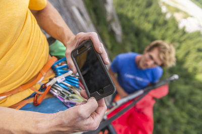 Climber looking at instruction on how to set up portaledge smartphone