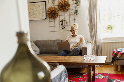 Smiling woman using laptop on sofa