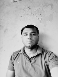 Portrait of young man standing against wall