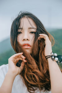 Close-up of beautiful young woman against sky