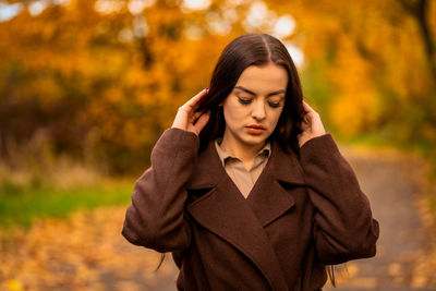 Portrait of a young woman in a brown coat in autumn