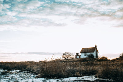 Houses on field against sky during winter