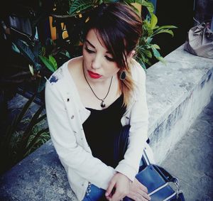 Young woman looking away while sitting outdoors