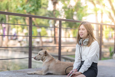 Young woman with dog sitting on mobile phone