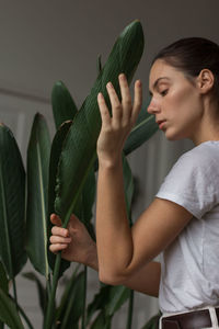 Side view of young woman holding plant