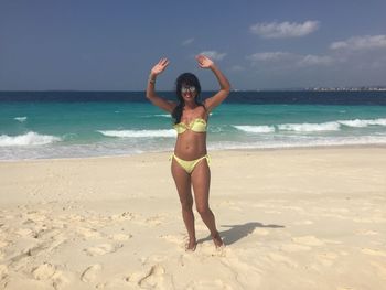 Full length portrait of young woman standing at beach