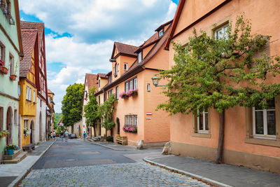 Street amidst trees and buildings against sky