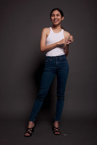 Portrait of young woman standing against gray background