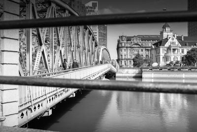 Footbridge over river in city against sky