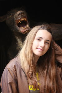 Portrait of confident girl with blond hair against wolf sculpture